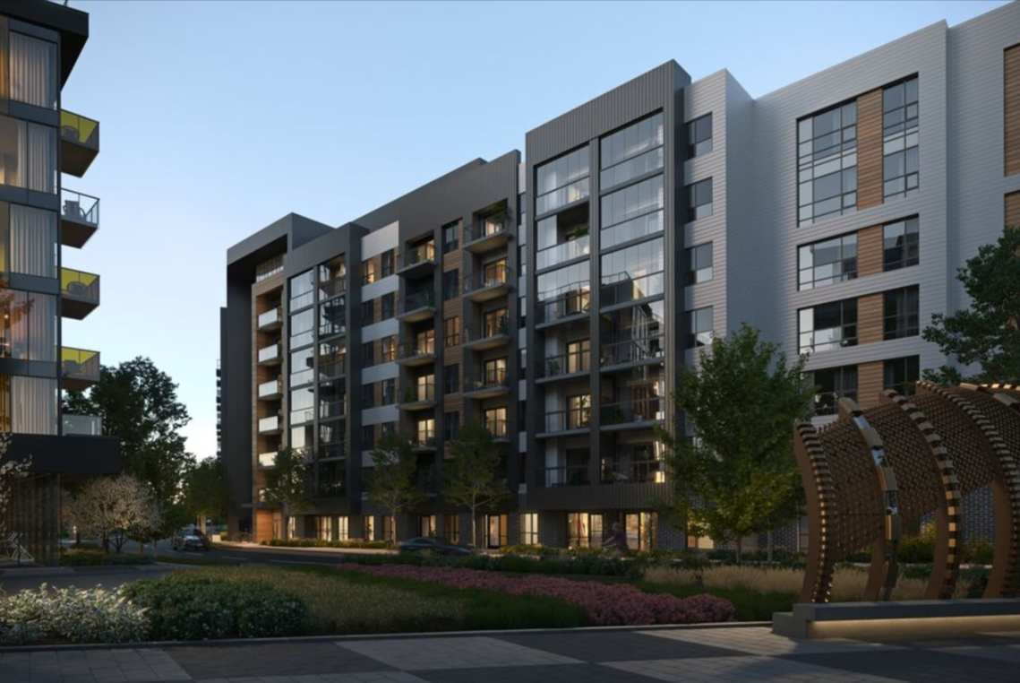 Modern apartment buildings with large glass windows and balconies, surrounded by landscaped gardens and trees in an urban residential area at dusk.