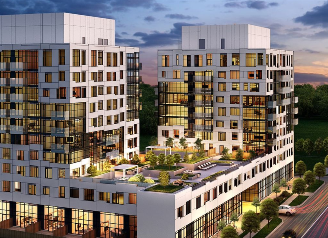 Modern apartment complex with two tall buildings featuring numerous windows, a rooftop garden, and outdoor amenities, set against a twilight sky and green landscape.