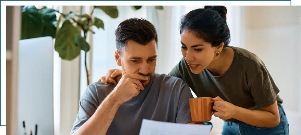 A man is anxious looking at his medical bill with his wife leaning in to comfort her husband.